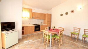 A compact kitchen with a dining area, a TV, and a small refrigerator.