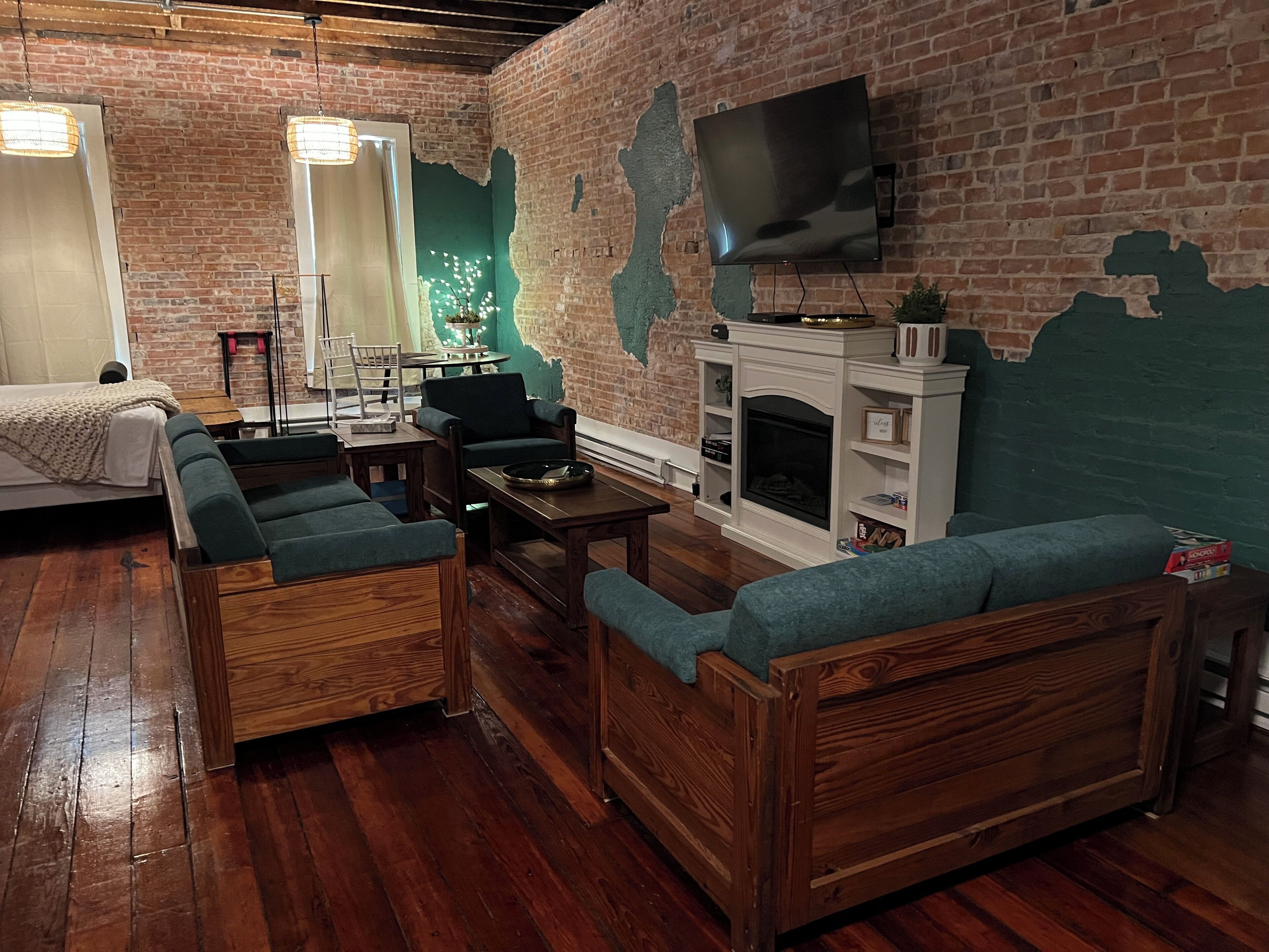 Ein gemütliches Wohnzimmer mit Backsteinwand, Kamin, Fernseher und Holzmöbeln.