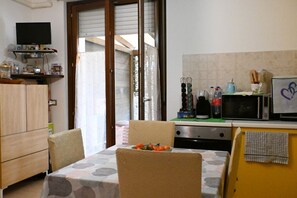 Une petite cuisine équipée d’une table à manger, de chaises, d’un four à micro-ondes et d’un téléviseur.