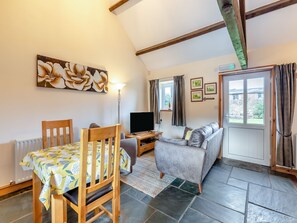 A cozy room with a dining table, a sofa, a TV, and a window with curtains. - Eight Byre - UK48913 (Allonby)