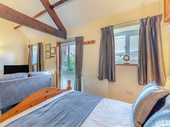 Un dormitorio con cama, ventana con cortinas, radiador y televisor.