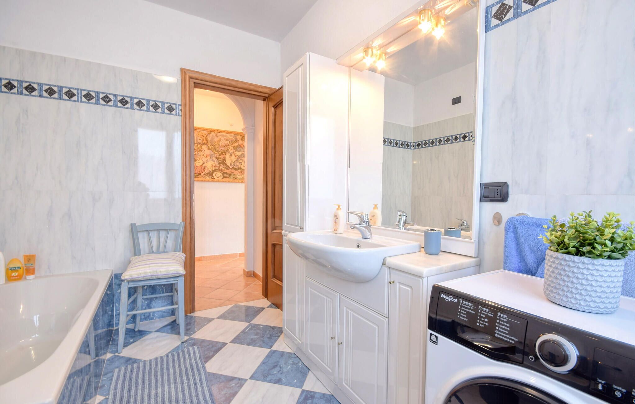 Un baño con lavamanos, espejo y lavadora.