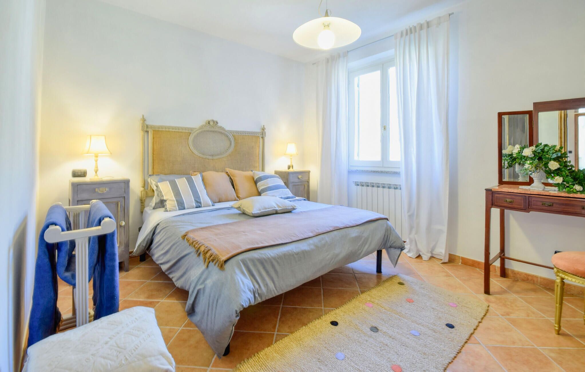 A bedroom with a bed, bedside tables, a dresser, a mirror, and a window with curtains.