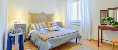 A bedroom with a bed, bedside tables, a dresser, a mirror, and a window with curtains.