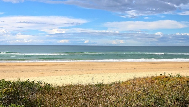 Una spiaggia con un litorale sabbioso e onde oceaniche.