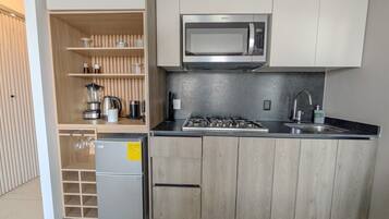 Eine kleine Küche mit Einbau-Mikrowelle, Gasherd und Kühlschrank.