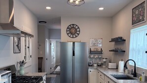 Una cocina moderna con un refrigerador de acero inoxidable, una estufa a gas y alacenas blancas.