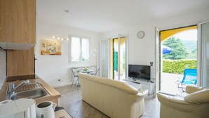 A modern living room with a sofa, a TV, and a dining area with chairs and a table. - 2 bedroom nice home in Imperia (Imperia)