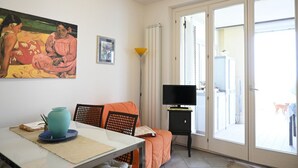 A room with a dining table, a sofa, a TV, and a painting on the wall. - P049 – Porto Recanati, comfortable studio apartment with sea view (Porto Recanati)
