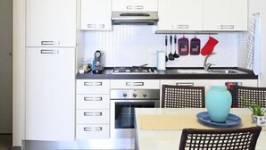 A compact kitchen with white cabinets, a stove, oven, and a sink. - P049 – Porto Recanati, comfortable studio apartment with sea view (Porto Recanati)