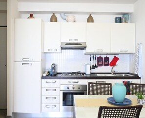 A compact kitchen with white cabinets, a stove, oven, and a sink.