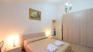 A bedroom with a bed, bedside lamps, a painting, a wardrobe, and a chandelier. - Stunning home in Poggio d'Acona (Poggio d'Acona)