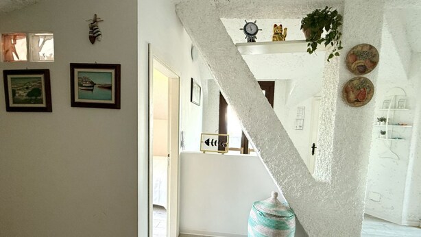 Un escalier avec un mur à texture, un tableau encadré, un vase et une petite plante.