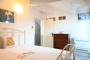 A bedroom with a bed, a dresser, a wall-mounted air conditioner, and a door leading to another room. - M416 – Marcelli, attic seen badly a few steps from the beach (Marcelli)