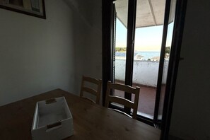 A room with a wooden table, a chair, and a window with a view of a beach.