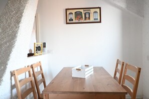 A dining area with a wooden table, four chairs, a framed picture on the wall, and a small shelf with items. - M416 – Marcelli, attic seen badly a few steps from the beach (Marcelli)