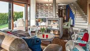 A modern living room with a fireplace, a staircase, and a view of the outdoors.