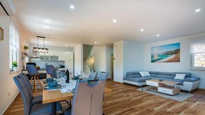 A modern living room with a dining area, a sofa, and a kitchen in the background. - Amazing home in Matulji (Matulji)