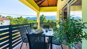 A balcony with a table set for two, chairs, and a potted plant. - Amazing home in Matulji (Matulji)