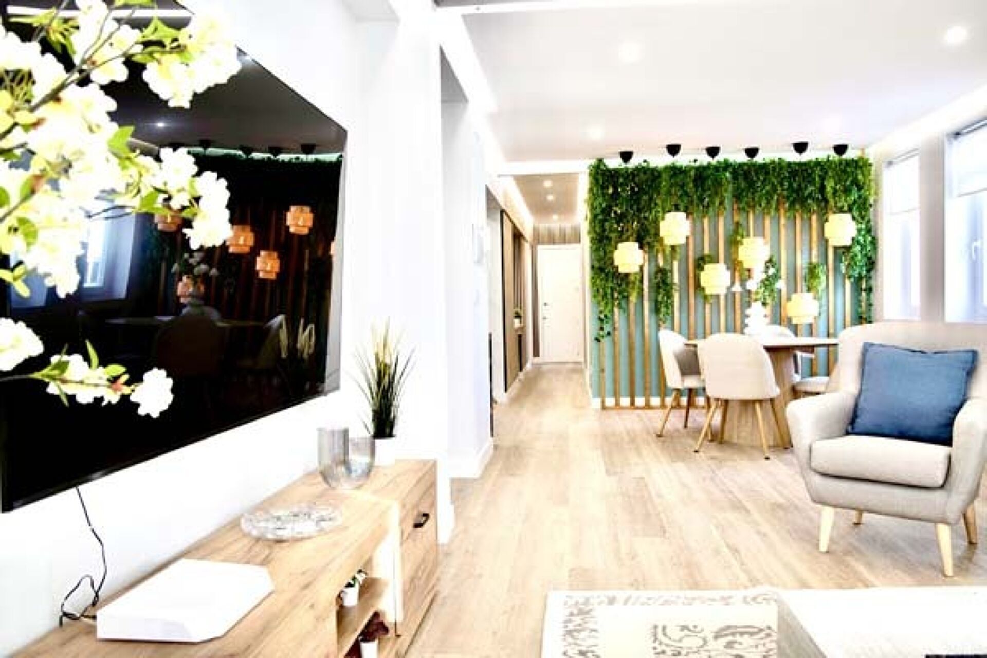 Uma sala de estar moderna com uma janela grande, uma área de jantar com parede verde e um espaço de estar.