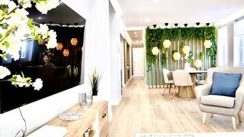 Uma sala de estar moderna com uma janela grande, uma área de jantar com parede verde e um espaço de estar.