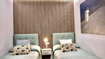 Un dormitorio con dos camas, una pared de listones de madera, una mesita de noche con lámpara y un cuadro en la pared.