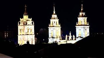 Vista nocturna de un edificio histórico con tres torres iluminadas.