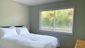 A bedroom with a bed, a window with blinds, and a wooden bench. - Hidden JEM Apartment-Hotel - Spacious Home Away From Home (Coal Harbour)