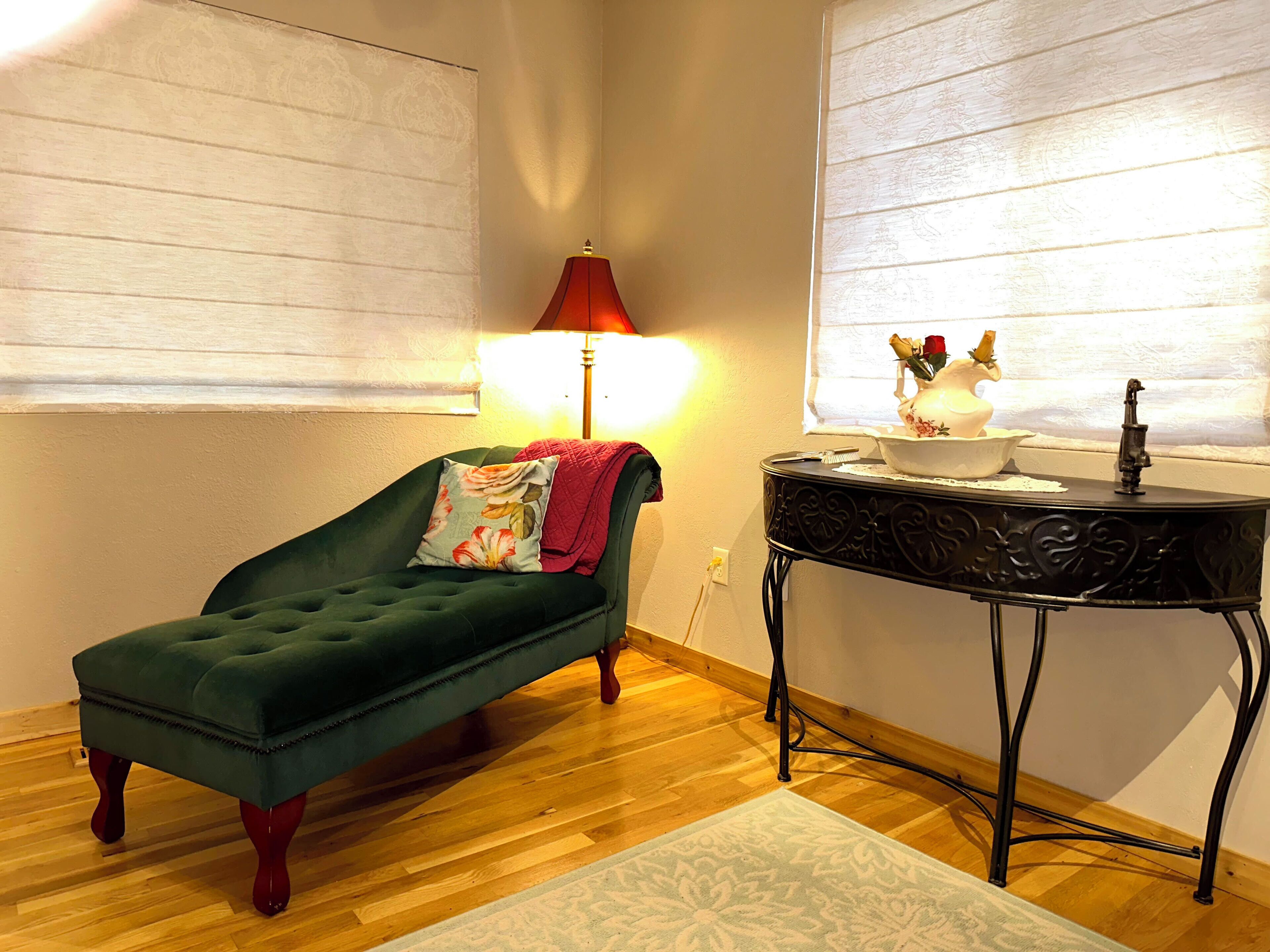 A cozy room with a green sofa, a small table with a vase, and a lamp.