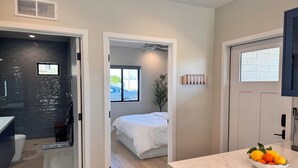 Ein modernes Hotelzimmer mit Badezimmer, Schlafbereich und Küchenzeile.