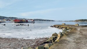 A coastal scene with a frozen water body, a stone breakwater, and a row of colorful buildings in the background. - Amazing home in Särö with WiFi (Särö)