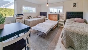 A cozy bedroom with two beds, a desk, and a chair. There are windows providing natural light and a view of the outside. - Amazing home in Särö with WiFi (Särö)