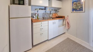 A compact kitchen with white cabinets, a wooden countertop, a sink, and a kettle on the microwave. - Amazing home in Särö with WiFi (Särö)