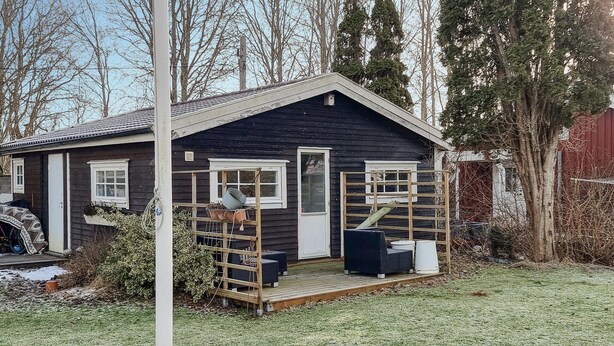 A small, dark wooden cabin with a porch, a ladder, and outdoor seating. - Amazing home in Särö with WiFi (Särö)
