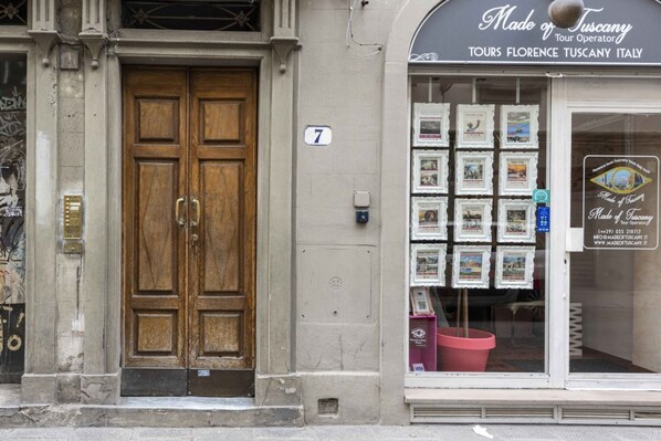 Ein Gebäude mit einer hölzernen Doppeltür, einem Schild mit der Nummer 7 und einem Schaufenster, das gerahmte Bilder zeigt.