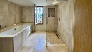 Un baño moderno con bañera, ducha y ventana con vistas al exterior.