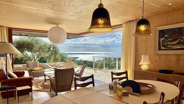 Un salón amplio con una gran mesa redonda, asientos cómodos y vista al mar.