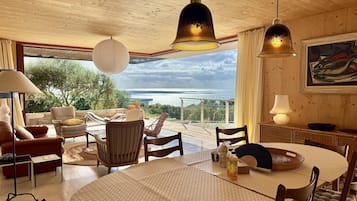 Un salon spacieux avec une grande table ronde, des sièges confortables et une vue sur la mer.