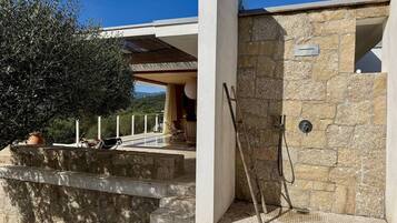 Een moderne villa met een stenen gevel, een houten terras en uitzicht op het omliggende landschap.