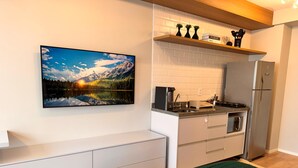 A modern kitchen with a built-in oven, a refrigerator, and a coffee maker on the countertop. - Studio Brooklin 1min from the subway and close to the consulate (Brooklin São Paulo)