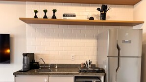 A modern kitchen with a built-in microwave, a coffee maker, and a refrigerator. - Studio Brooklin 1min from the subway and close to the consulate (Brooklin São Paulo)