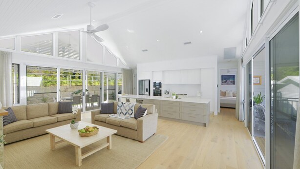 A spacious living area with a large sofa, a coffee table, and a kitchen in the background.