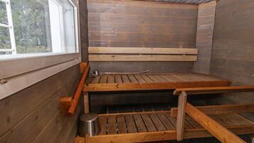 Una sauna con panche di legno e un contenitore metallico, probabilmente per acqua o vapore.