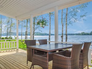 A covered outdoor area with a table and chairs, overlooking a body of water and trees. - Villa onnela by Interhome (Hämeenkyrö)