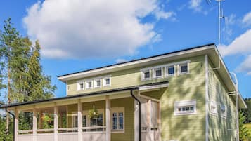 Une maison à deux étages avec un porche, une antenne parabolique et un ciel dégagé.