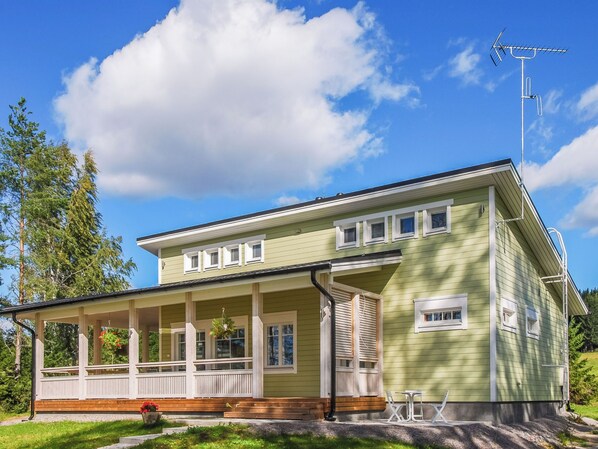 A two-story house with a porch, a satellite dish, and a clear sky.