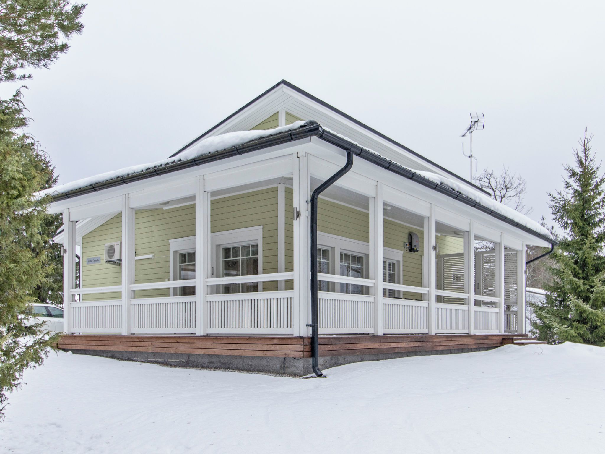 Una casa de dos pisos con un porche cubierto y un techo cubierto de nieve.