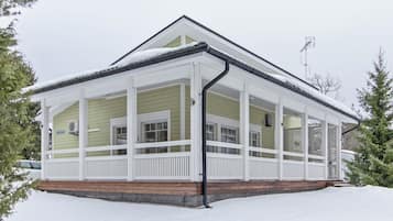 A two-story house with a covered porch and a snow-covered roof.