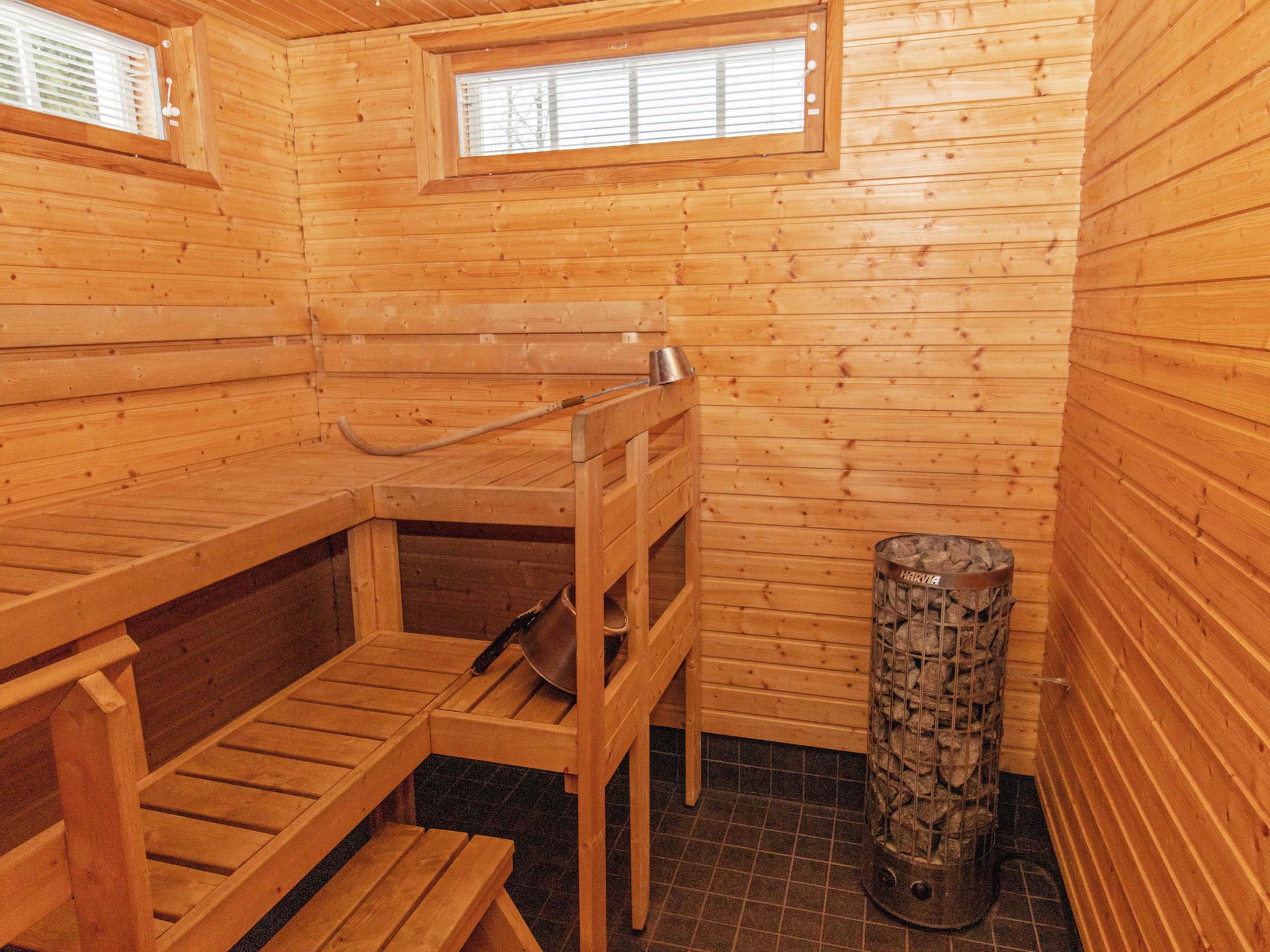 Puinen sauna, jossa on penkit, pieni ikkuna ja metallinen astia tuhkalle.