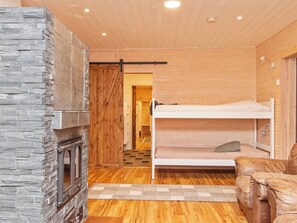 Une pièce chaleureuse avec une cheminée en pierre, des lits superposés en bois et un plancher en bois.